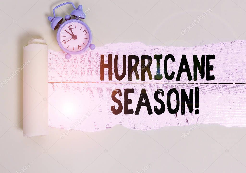 Writing note showing Hurricane Season. Business photo showcasing time when most tropical cyclones are expected to develop Alarm clock and torn cardboard on a wooden classic table backdrop.