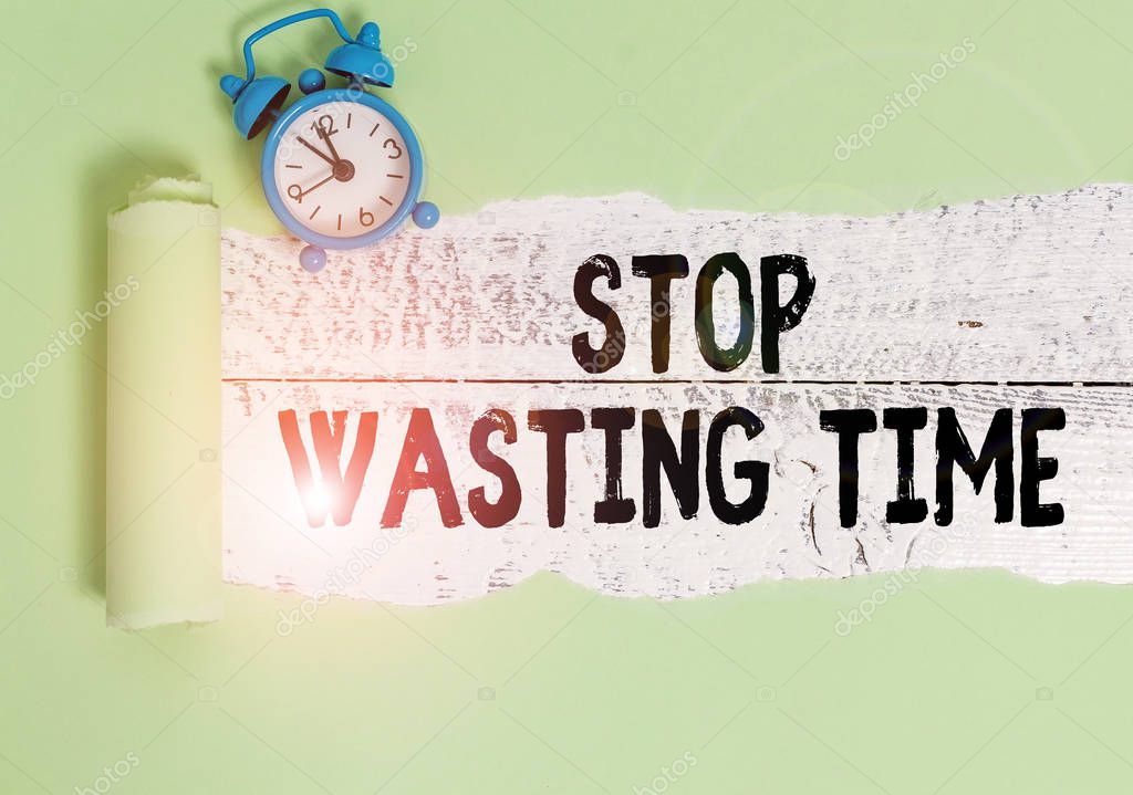 Writing note showing Stop Wasting Time. Business photo showcasing advising demonstrating or group start planning and use it wisely Alarm clock and torn cardboard on a wooden classic table backdrop.