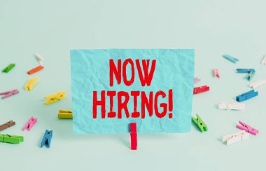 Şimdi işe alındığını gösteren bir not yazıyorum. İş fotoğraflarında, gelecekteki çalışanlarla iş ilişkisinin değerlendirildiği gösteriliyor. Renkli çamaşır tokası dikdörtgeni şeklinde kağıt açık mavi arkaplan.