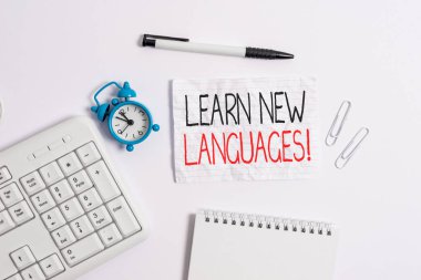 Conceptual hand writing showing Learn New Languages. Business photo showcasing developing ability to communicate in foreign lang Copy space on note paper with clock and pencil on the table. clipart