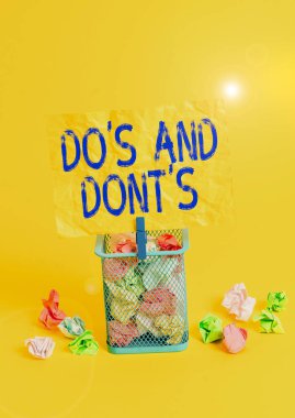 Do S ve Don 't S' un iş fotoğraflarının el yazısını gösteren kavramsal el yazısı bazı aktiviteler veya eylemlerle ilgili kurallar veya gelenekler çöp kutusunun buruşturulmuş kağıt çamaşır mandalı ofisi sarı tedarik eder..