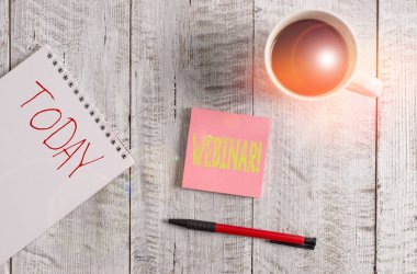 Webinar 'ı gösteren bir not yazıyorum. İş fotoğrafı tanıtım semineri ya da internet sitesinde yer alan diğer sunum türleri ahşap masanın üzerindeki bir fincan sade kahvenin yanına yerleştirilmiştir..
