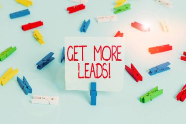Get More Leads 'i gösteren bir not yazıyorum. İş fotoğraflarında tüketicinin ilgisini gösteren ya da araştırma ürünleri ya da hizmetler Renkli çamaşır mandalı kağıtları boş hatırlatıcı mavi ofis.