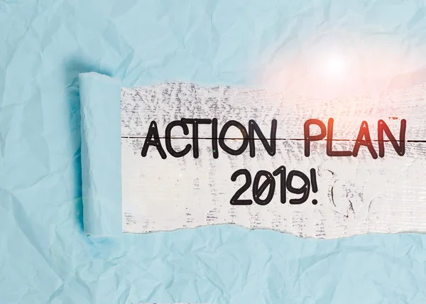 Text sign showing Action Plan 2019. Conceptual photo proposed strategy or course of actions for current year Cardboard which is torn in the middle placed above a wooden classic table.