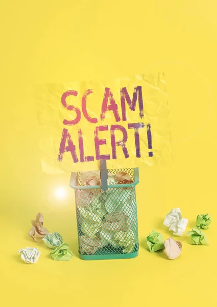 Conceptual hand writing showing Scam Alert. Business photo text fraudulently obtain money from victim by persuading him Trash bin crumpled paper clothespin office supplies yellow.