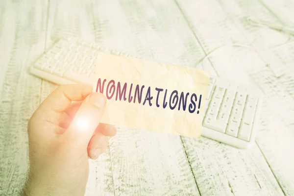 Sms-teken met nominaties. Conceptuele foto actie van nomineren of staat wordt genomineerd voor prijs man met kleurrijke herinnering vierkante vorm papier wit toetsenbord houten vloer. — Stockfoto