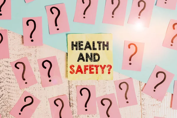 Text sign showing Health And Safety Question. Conceptual photo regulations and procedures to prevent accident or injury Scribbled and crumbling papers with thick cardboard above wooden table.