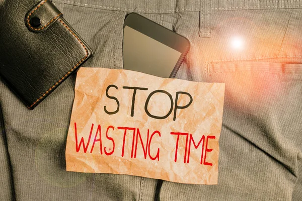 ［Stop Wasting Time］を示す書き込みノート。アドバイスやグループの開始計画を実証し、賢明にそれを使用するビジネス写真財布付きズボンフロントポケット内のスマートフォンデバイス. — ストック写真