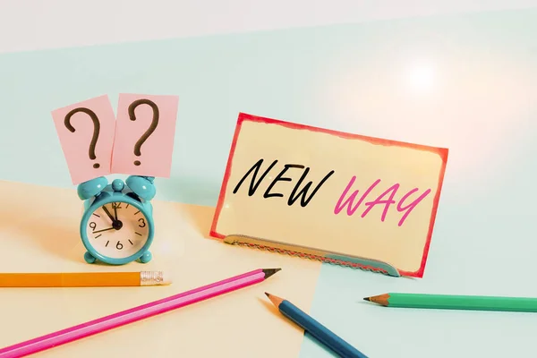 Handwriting text New Way. Concept meaning To move from one place To make changes and do something in a new way Mini size alarm clock beside stationary placed tilted on pastel backdrop.
