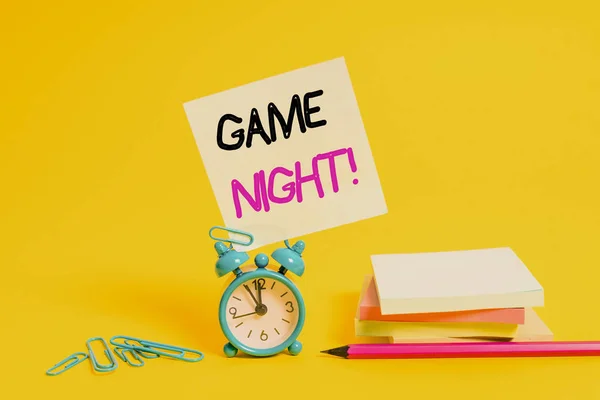 Conceptual hand writing showing Game Night. Business photo text usually its called on adult play dates like poker with friends Alarm clock pencil clips note stacked notepads colored background. — Stock Photo, Image
