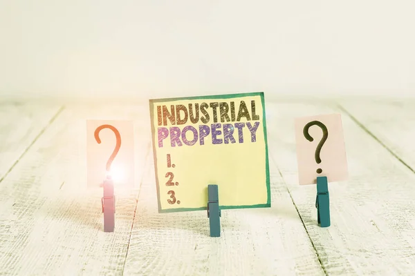 Håndskriftstekst: Industrial Property. Betegnelse som betyr immateriell eierskap av et varemerke eller et patent, avskrevet og smuldrende ark med binders plassert på trebordet . – stockfoto