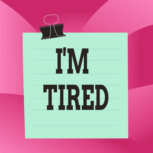 Handwriting text I M Tired. Concept meaning drained of strength and energy Fatigued to the point of exhaustion Paper lines binder clip cardboard blank square notebook color background.