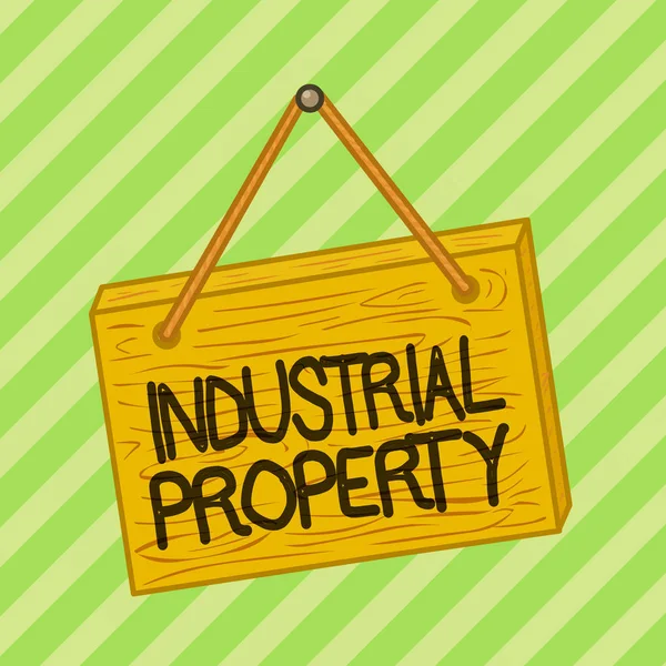 Text sign showing Industrial Property. Conceptual photo the intangible ownership of a trademark or patent Square rectangle unreal cartoon wood wooden hang down on the coloured wall.