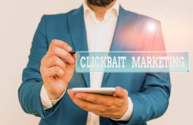 Clickbait Pazarlama 'yı gösteren bir not yazıyorum. Sayfa görüntüsü oluşturmayı amaçlayan iş fotoğrafı içeriği: Mavi süitteki iş adamı, dizüstü bilgisayarı parmağıyla işaret ediyor..