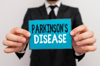 Parkinson S hastalığını gösteren bir not yazıyorum. Hareketi etkileyen iş fotoğraflarında sinir sistemi bozukluğu var. Erkek insan resmi iş kıyafeti giyiyor..