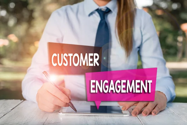Handwriting text Customer Engagement. Concept meaning the emotional connection between a customer and a brand Female business person sitting by table and holding mobile phone.