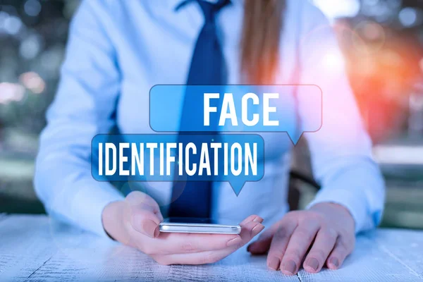Word writing text Face Identification. Business concept for analyzing patterns based on the demonstrating s is facial contours Female business person sitting by table and holding mobile phone.