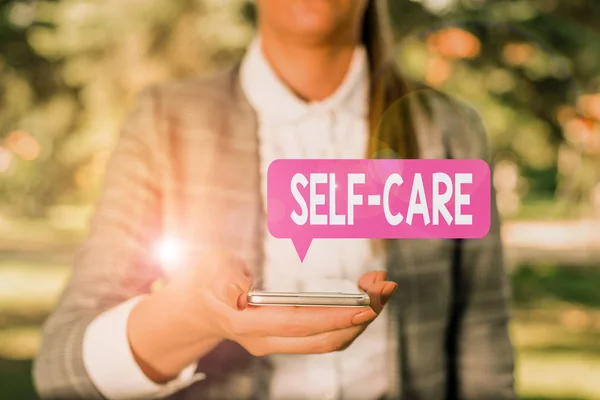 Writing note showing Self Care. Business photo showcasing the practice of taking action to improve one s is own health Woman in grey suites holds mobile phone. — Stock Photo, Image