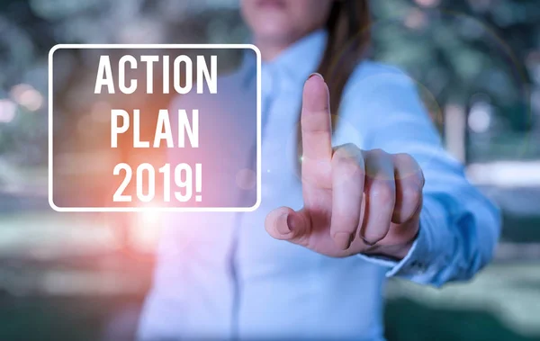 Handwriting text writing Action Plan 2019. Concept meaning proposed strategy or course of actions for current year Woman in a blue business shirts pointing with her finger into empty space.