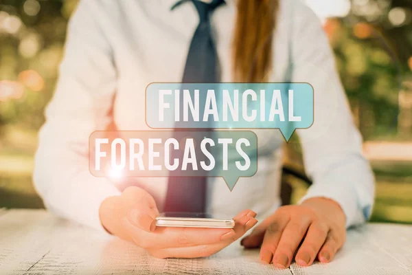 Tekst pisania słów Prognozy finansowe. Koncepcja biznesowa szacowania przyszłych wyników finansowych dla spółki Kobieta-przedsiębiorca siedząca przy stole i trzymająca telefon komórkowy. — Zdjęcie stockowe
