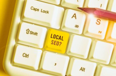 Yerel Seoquestion 'u gösteren kavramsal el yazısı. İş fotoğrafı, yerel işinizi online olarak pazarlamanın inanılmaz etkili bir yolunu gösteriyor. Beyaz arkaplanının üstündeki nota kağıdıyla birlikte beyaz pc klavye.