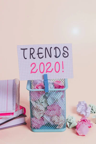 Conceptual hand writing showing Trends 2020. Business photo text general direction in which something is developing or changing Trash bin crumpled paper clothespin office supplies yellow.