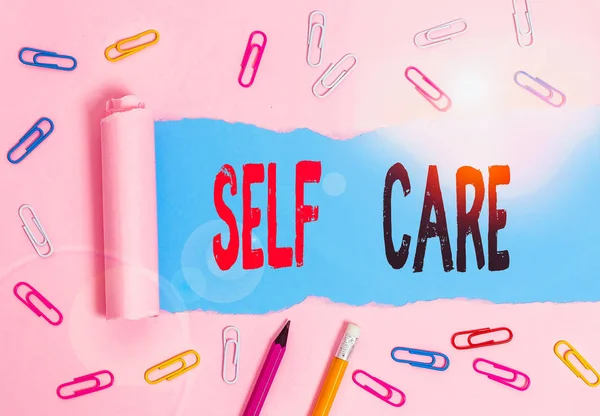 Handwriting text writing Self Care. Concept meaning the practice of taking action to improve one s is own health Stationary and torn cardboard placed above a plain pastel table backdrop. — Stock Photo, Image