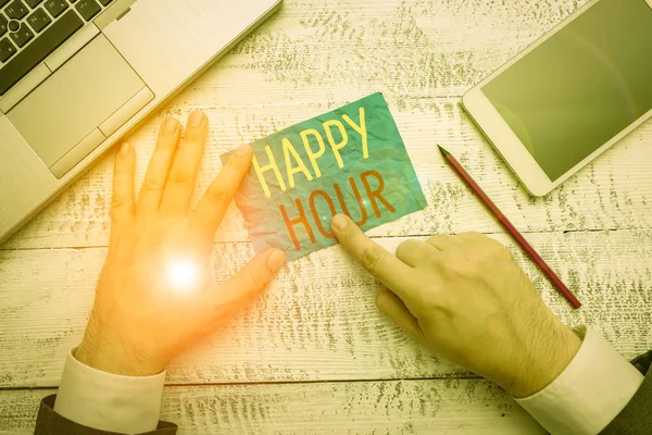 Conceptual hand writing showing Happy Hour. Business photo text when drinks are sold at reduced prices in a bar or restaurant Hand hold note paper near writing equipment and smartphone.