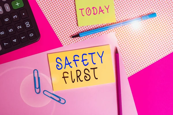 Handwriting text writing Safety First. Concept meaning used to say that the most important thing is to be safe writing equipments with stationary and plain note paper placed on the table.