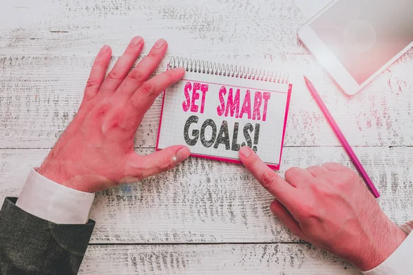 Text sign showing Set Smart Goals. Conceptual photo list to clarify your ideas focus efforts use time wisely Hand hold note paper near writing equipment and modern smartphone device. — Stock Photo, Image