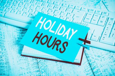 Holiday Hours 'u gösteren bir not yazıyorum. Çalışanların iş konsepti, her saat için normal ücretlerinin iki katını alır. Anımsatıcı broşu ve çivilenmiş ahşap çarşaf.