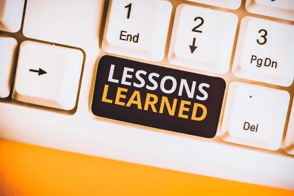 Conceptual hand writing showing Lessons Learned. Business photo text the knowledge or understanding gained by experience White pc keyboard with note paper above the white background. — Stock Photo, Image