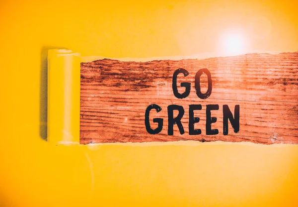 Κείμενο γραφής λέξεων, πράσινο. Επιχειρηματική ιδέα για τη λήψη πιο φιλικών προς το περιβάλλον αποφάσεων, όπως μείωση ανακύκλωσης χαρτόνι το οποίο σχίζεται στη μέση τοποθετείται πάνω από ένα ξύλινο κλασικό τραπέζι. — Φωτογραφία Αρχείου