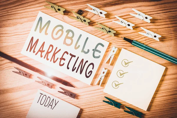 Conceptual hand writing showing Mobile Marketing. Business photo showcasing promotional activity designed for delivery to cell phones Colored crumpled papers wooden floor background clothespin.