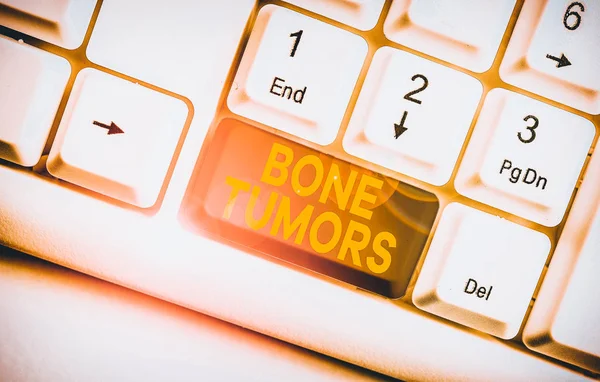 Writing note showing Bone Tumors. Business concept for can be either benign or malignant growths found in the bone White pc keyboard with note paper above the white background