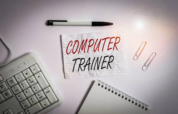 Text sign showing Computer Trainer. Business photo showcasing instruct and help users acquire proficiency in computer White pc keyboard with empty note paper and pencil above white background