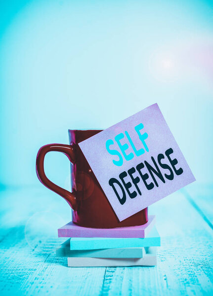 Handwriting text Self Defense. Conceptual photo the act of defending one s is demonstrating when physically attacked Coffee cup blank sticky note stacked note pads retro retro wooden table