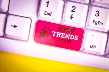 Yeni Trendler 2019'u gösteren not yazı. Bir şeyin beyaz arka plan üzerinde not kağıdı ile Beyaz pc klavyesi geliştirdiği genel yönü gösteren iş fotoğrafı.