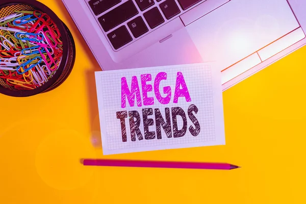 Conceptual hand writing showing Mega Trends. Business photo text powerful phenomena impacting the foundations of our world Trendy laptop pencil squared paper container colored background. — 스톡 사진