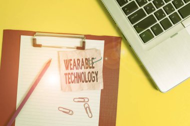 Giyilebilir Teknoloji 'yi gösteren bir not yazıyorum. Aksesuar olarak takılabilen elektronik cihazlar için iş konsepti dizüstü bilgisayar kağıt kağıtları kalem ezilmiş arkaplan rengini kırpıyor