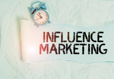 El yazısı, metin yazımı, Nüfuz Pazarlaması. Bir markayı sürmek için anahtar liderleri kullanmak alarm saatini piyasaya sürmek ve karton parçalarını düz pastel masa arkaplanının üzerine yerleştirmektir.