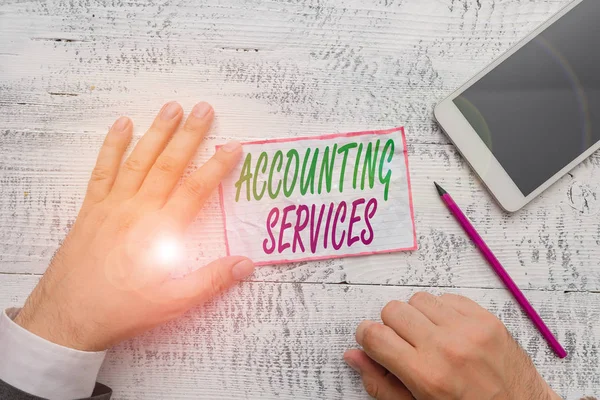 Conceptual hand writing showing Accounting Services. Concept meaning analyze financial transactions of a business or a demonstrating Hand hold note paper near writing equipment and smartphone