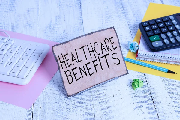 Text sign showing Healthcare Benefits. Business photo showcasing use the health services without risk of financial ruin Notepaper stand on buffer wire in between computer keyboard and math sheets