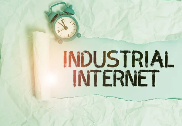 Handwriting text writing Industrial Internet. Conceptual photo use of the internet of things in industrial sectors Alarm clock and torn cardboard placed above plain pastel table backdrop