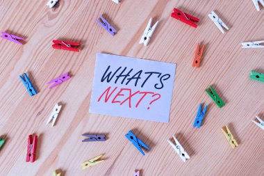 Text sign showing What S Is Nextquestion. Business photo showcasing Uncertainty about the following plan or actions to do Colored clothespin papers empty reminder wooden floor background office
