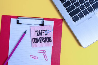 Writing note showing Traffic Conversions. Business concept for visitor who has been converted into a client or customer Laptop clipboard paper sheet clips pencil crushed colored background
