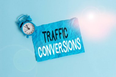 Conceptual hand writing showing Traffic Conversions. Concept meaning visitor who has been converted into a client or customer Metal vintage alarm clock crush sheet sky colored background