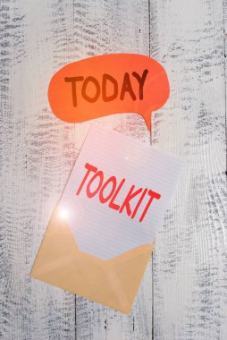 Text sign showing Toolkit. Business photo text set of tools kept in a bag or box and used for a particular purpose Front view open envelop speech bubble paper sheet lying wooden background