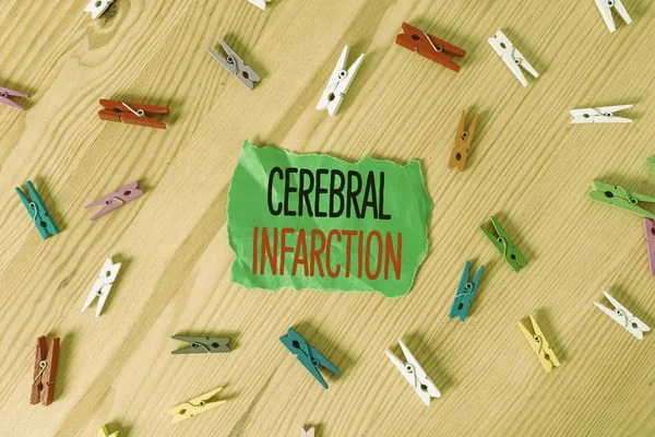 Conceptual hand writing showing Cerebral Infarction. Concept meaning focal brain necrosis due to complete and long ischemia Colored crumpled papers wooden floor background clothespin