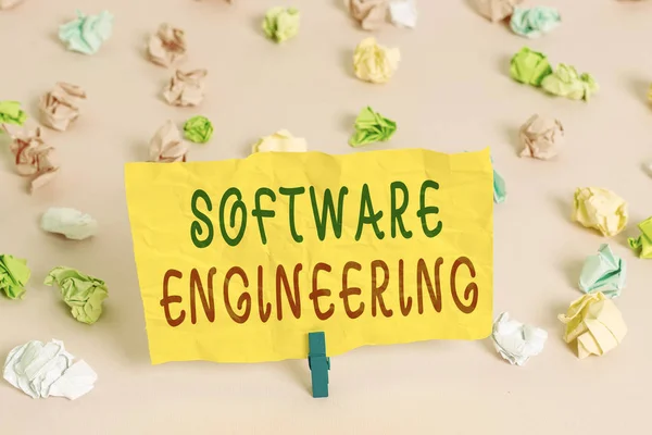 Handwriting text writing Software Engineering. Conceptual photo apply engineering to the development of software Colored crumpled papers empty reminder pink floor background clothespin